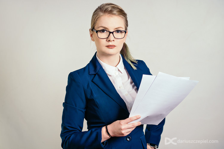 kobieta w okularach i z dokumentami pozuje podczas sesji studyjnej w Krakowie